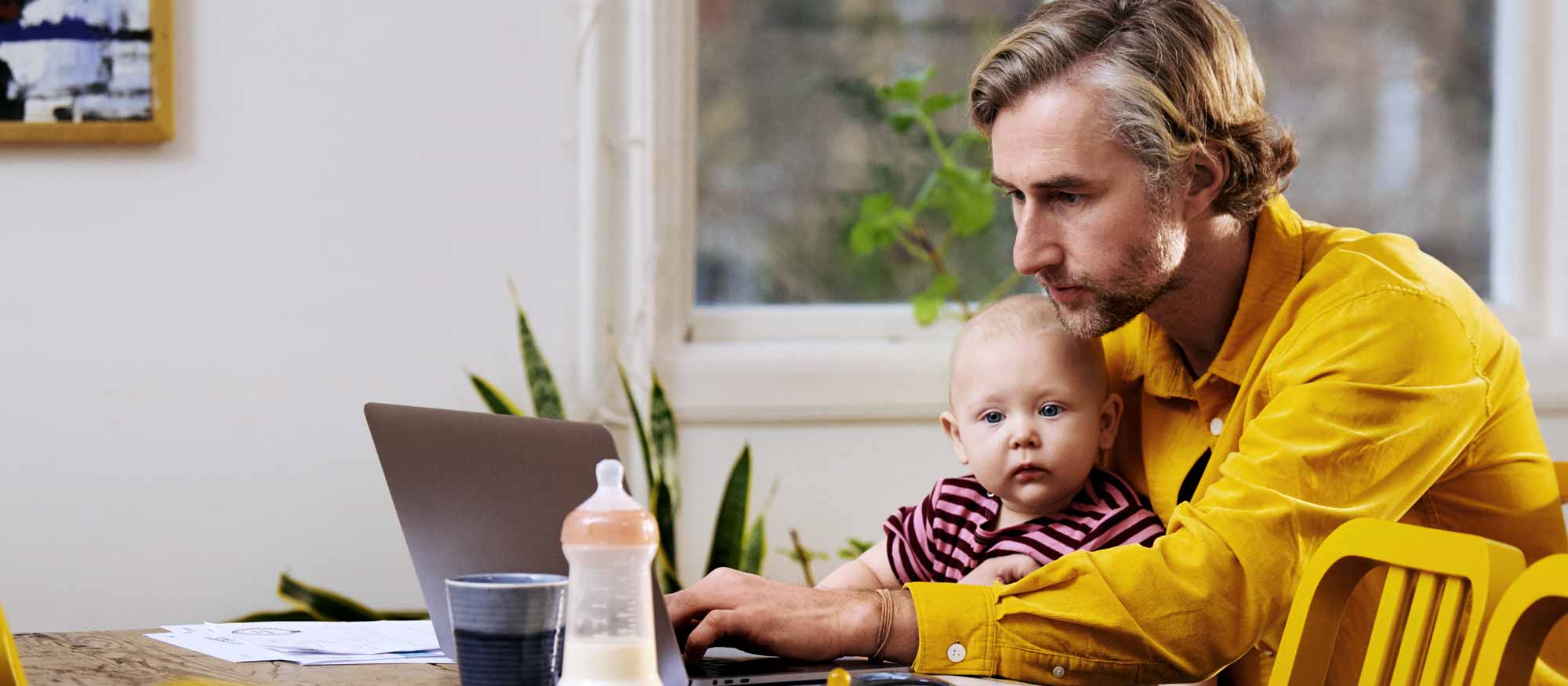 Pappa tittar på dator med bebis i knät